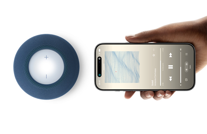 Un HomePod mini 2 et un iPhone, une main tient l’iPhone à côté du HomePod mini 2 bleu pour illustrer la fonctionnalité Handoff