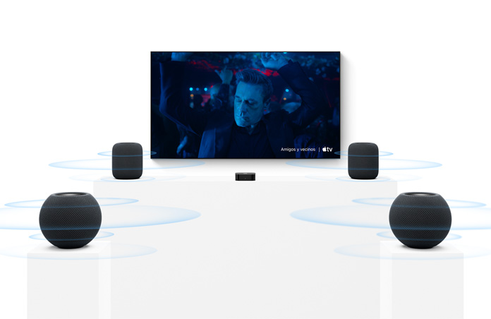 Apple TV 4K, pantalla de TV, dos parlantes HomePod color medianoche a la izquierda y a la derecha, dos parlantes HomePod mini 2 color medianoche en primer plano, ondas de sonido concéntricas que se propagan desde cada parlante