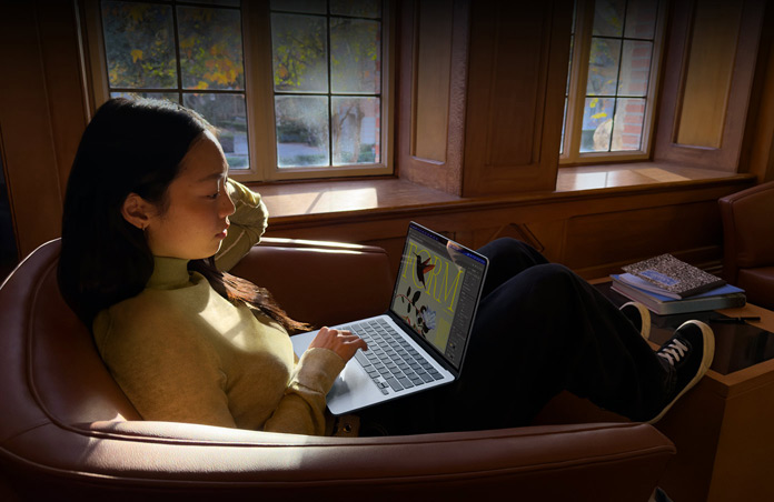 Une personne assise dans un fauteuil utilise son MacBook Air