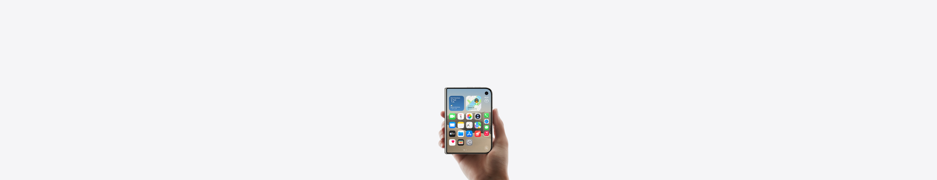 iPhone Duo, finition blanc stellaire, fermé, tenu par une main, montrant l’écran externe qui affiche l’écran d’accueil avec des apps et des widgets.