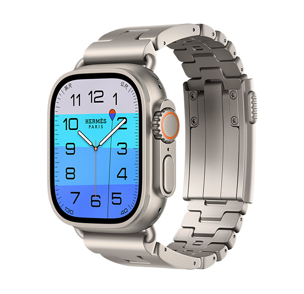 原色鈦金屬錶殼 Apple Watch Hermès Ultra 4,採用深海尋秘指針錶面 (時針、分針與秒針,以及水深複雜功能,橘色的浮標漂浮在透藍的海面上,海面由淺藍漸變至中藍),右側外觀上有數位錶冠、凸起的側邊按鈕,搭配 Gris Titane 鈦灰色 Grand H Titane 錶帶