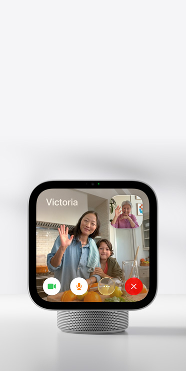 Un Apple HomeView montrant un appel vidéo FaceTime, avec une femme et son enfant qui font un signe de la main, et une femme plus âgée dans une petite fenêtre