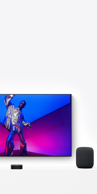 Une Apple TV 4K et un HomePod, couleur minuit, un écran de télévision affiche une personne artiste vêtue d’une tenue argent métallique