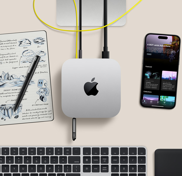 Laualoleva hõbedase Mac mini pealtvaade, mille liidestesse on ühendatud juhtmed ja mälupulk, kõrval juhtmevaba klaviatuur, trackpad, iPhone ja märkmik